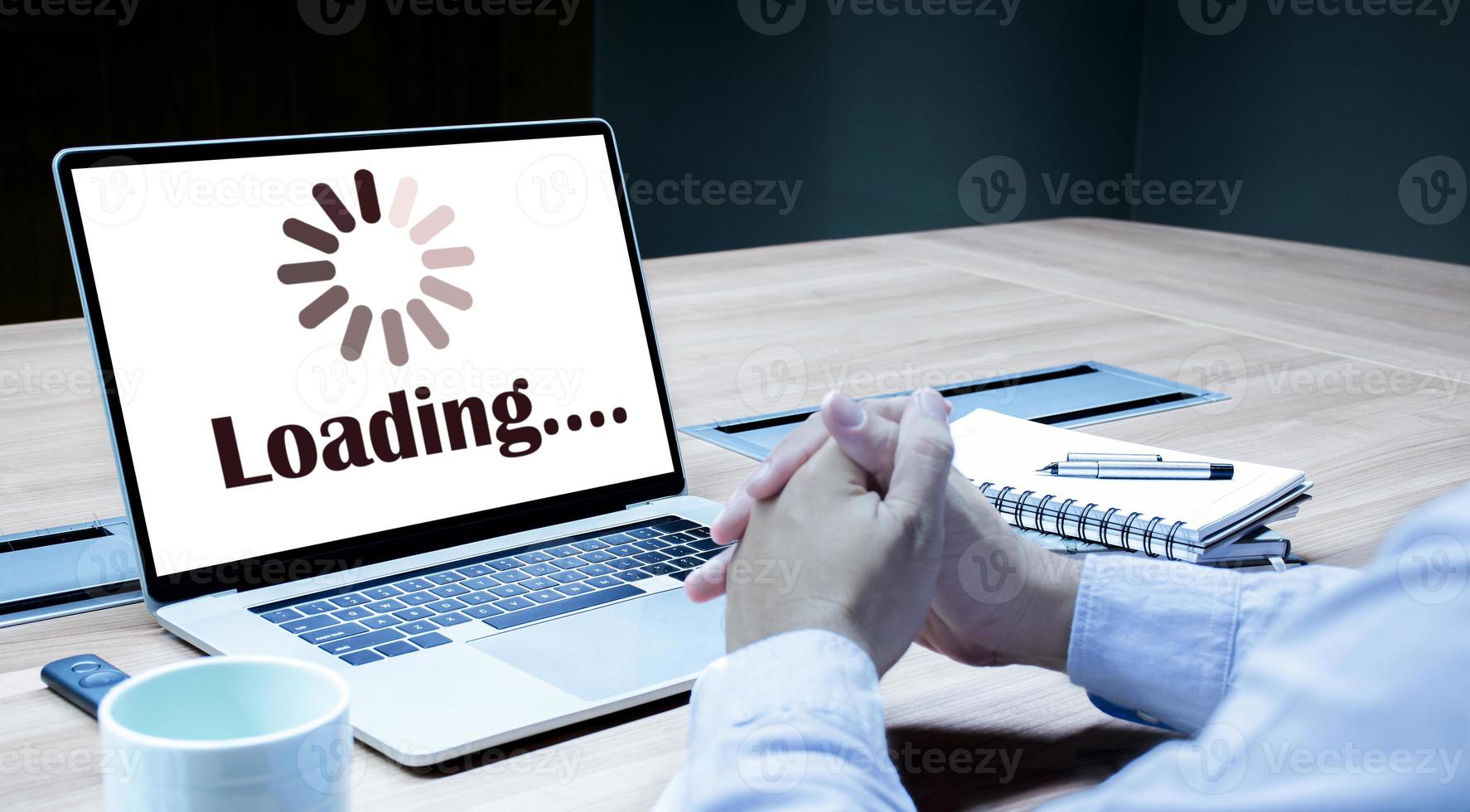 Businessman hands clasped together with icon loading on display laptop photo