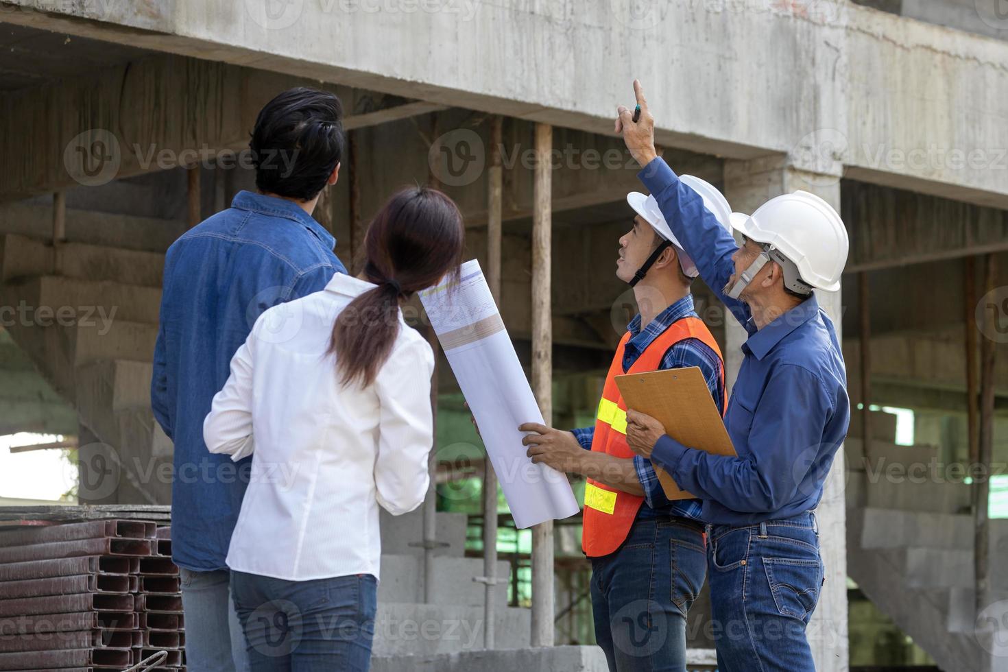 Newly wed couple is meeting with engineering contractor at their under construction house to inspect the building progress and quality control for home ownership and real estate development concept photo