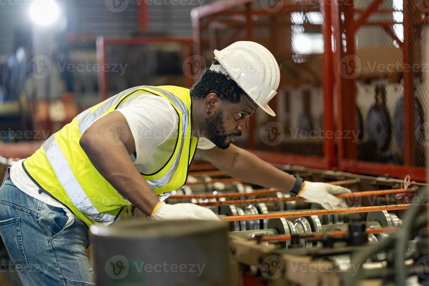 African American industrial worker is checking the setup value of metal sheet roll forming machine inside roof factory for safety industry construction concept photo