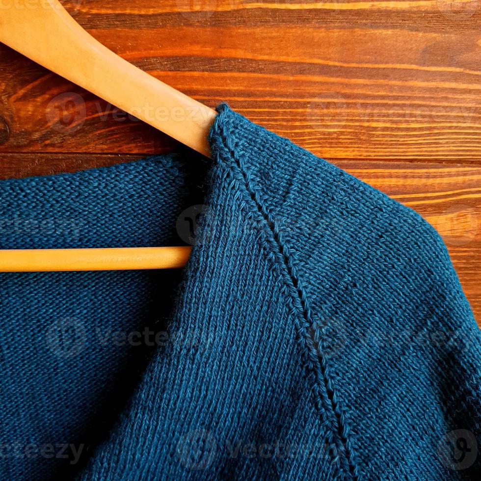 Handmade sweater. Knitted fabric from a green thread on a brown background. photo