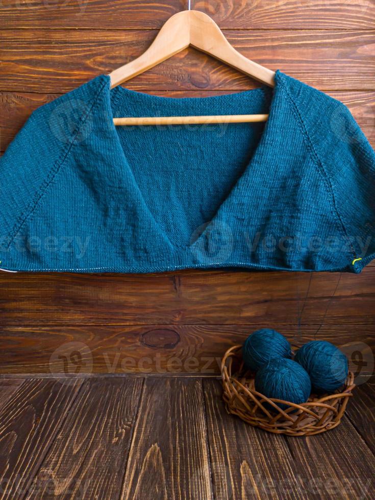 Handmade sweater. Knitted fabric from a green thread on a brown background. photo