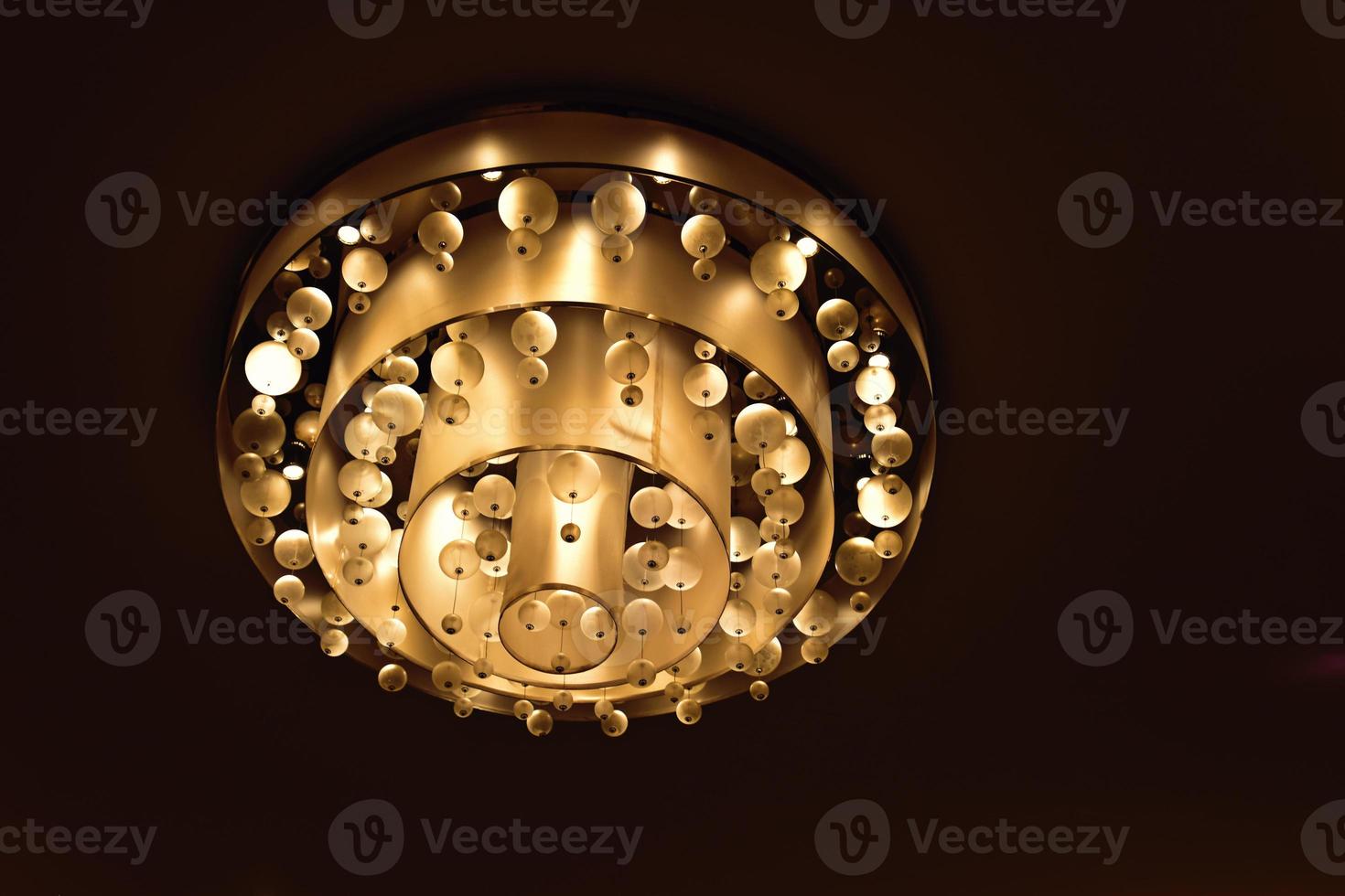 an  abstract background with an original glowing chandelier on the ceiling photo