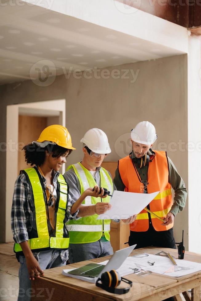 Architect caucasian man and woman working with colleagues mixed race in the construction site. Architecture engineering on big project. Building in construction process interior. photo