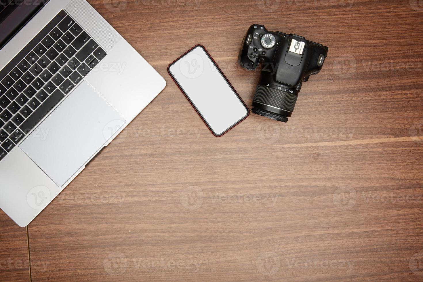 un ordenador portátil y un cámara en un de madera mesa foto