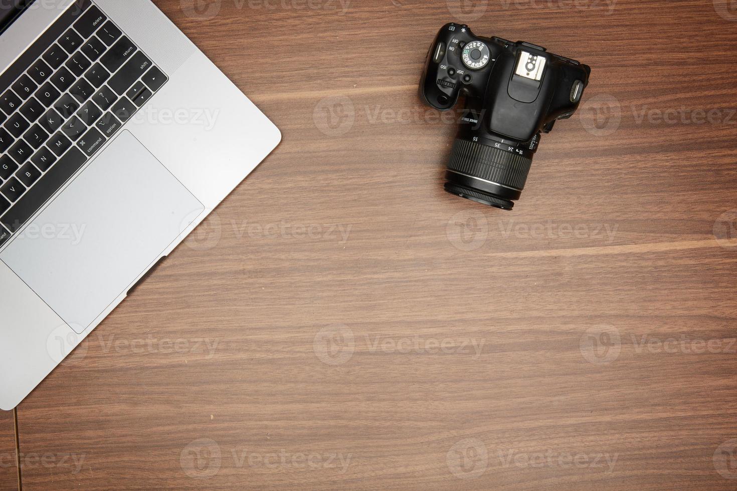 A laptop and a camera on a wooden table photo