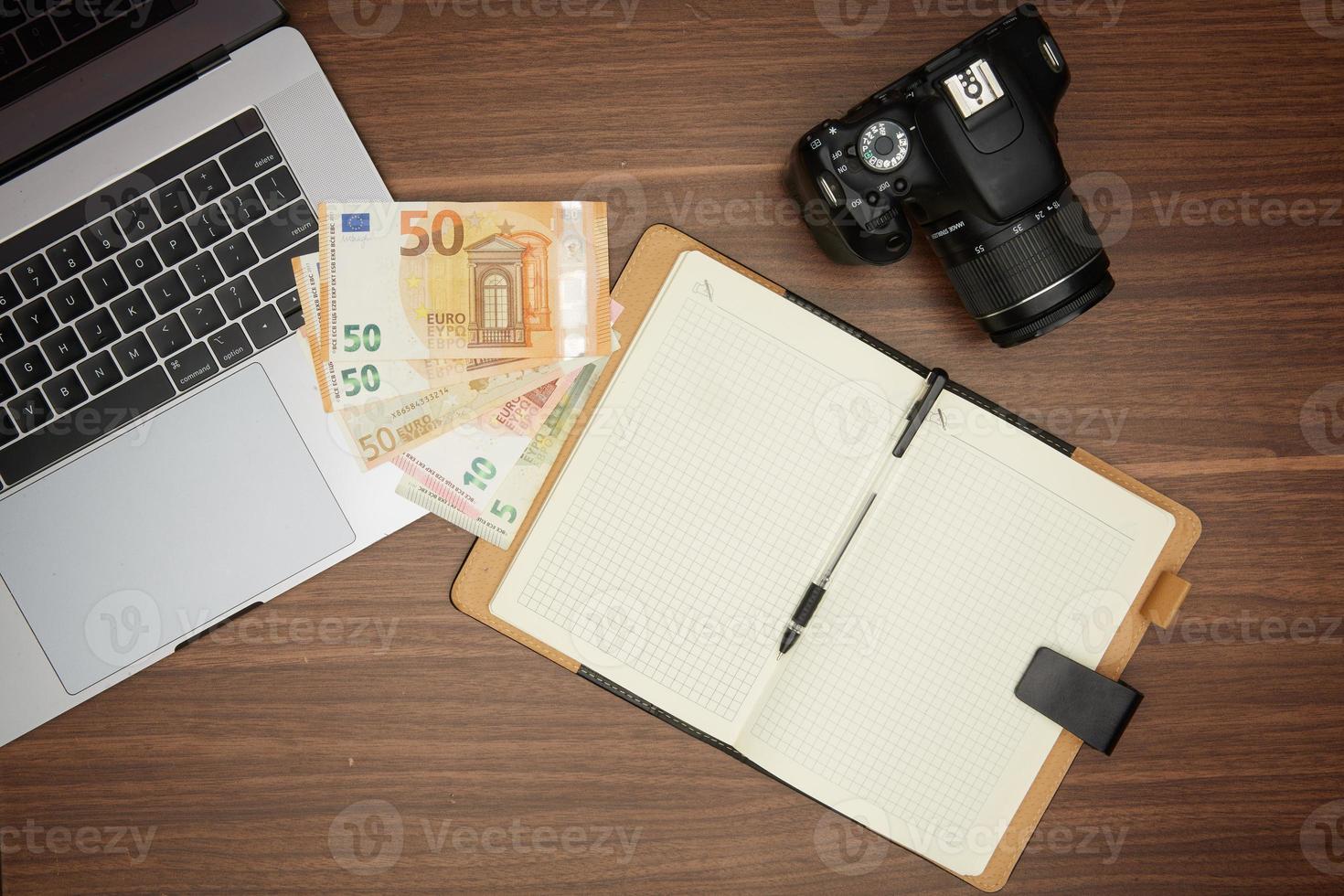 A laptop and a camera on a wooden table photo