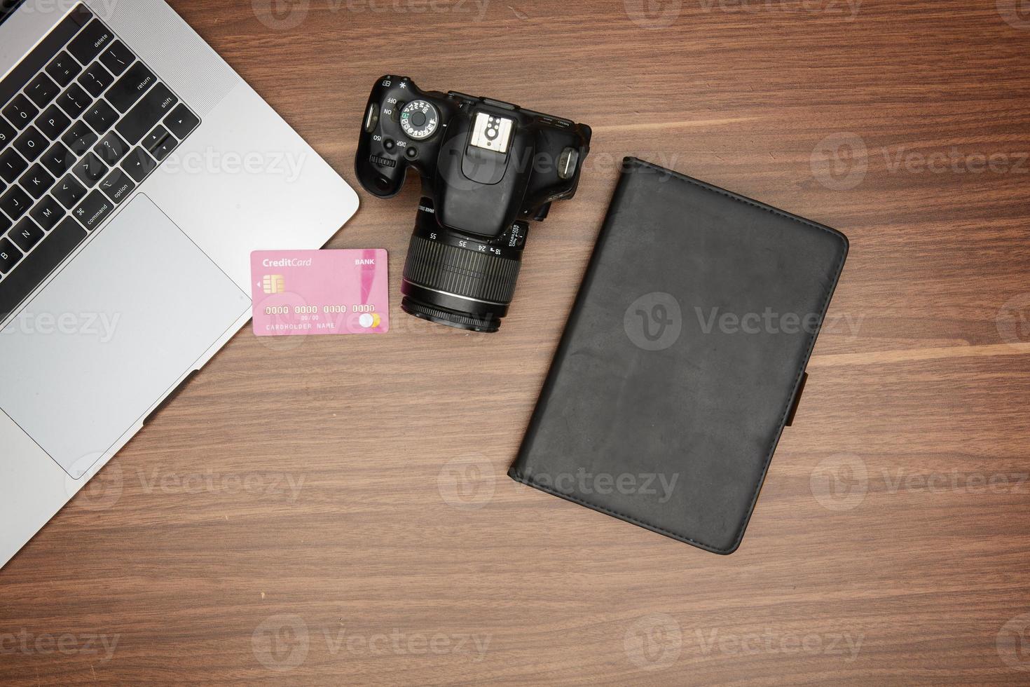 A laptop and a camera on a wooden table photo