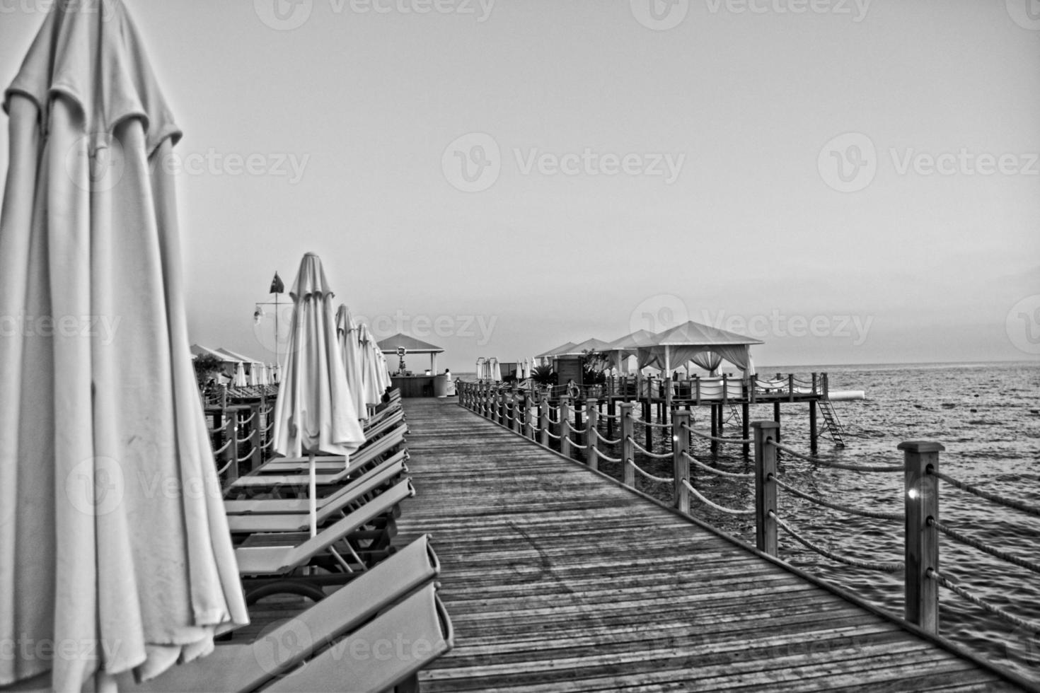 holiday landscape by the sea during sunset with sun loungers and umbrellas on the pier photo