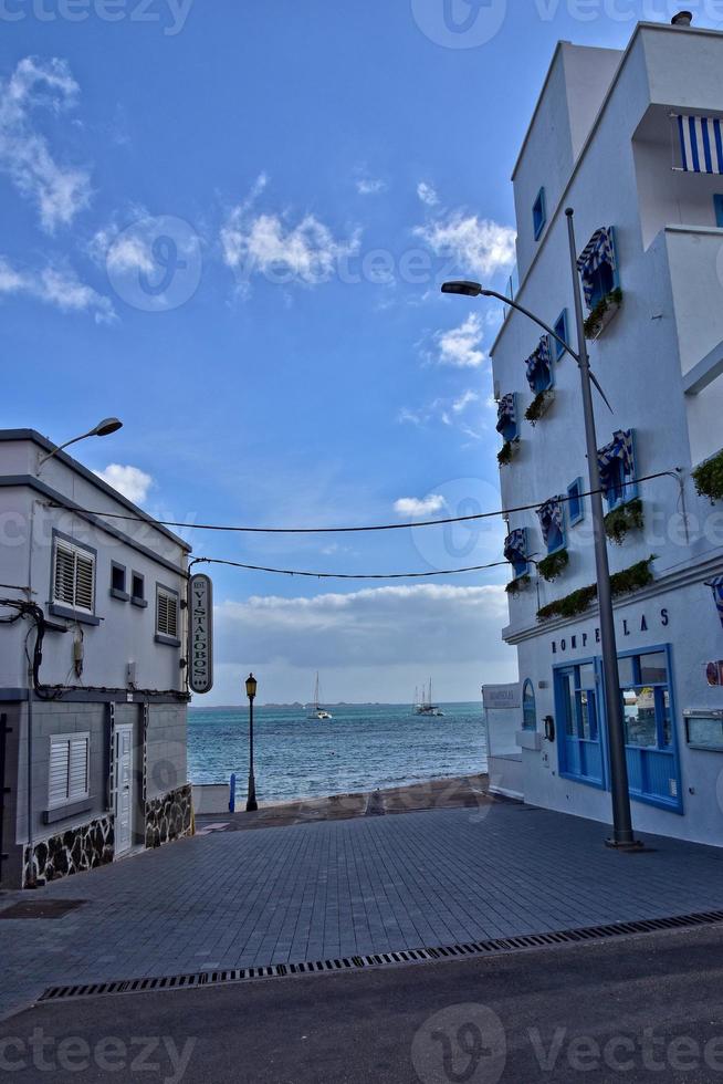 ver de el blanco casas con azul persianas en el antecedentes de el océanos en el Español isla de furertaventra foto