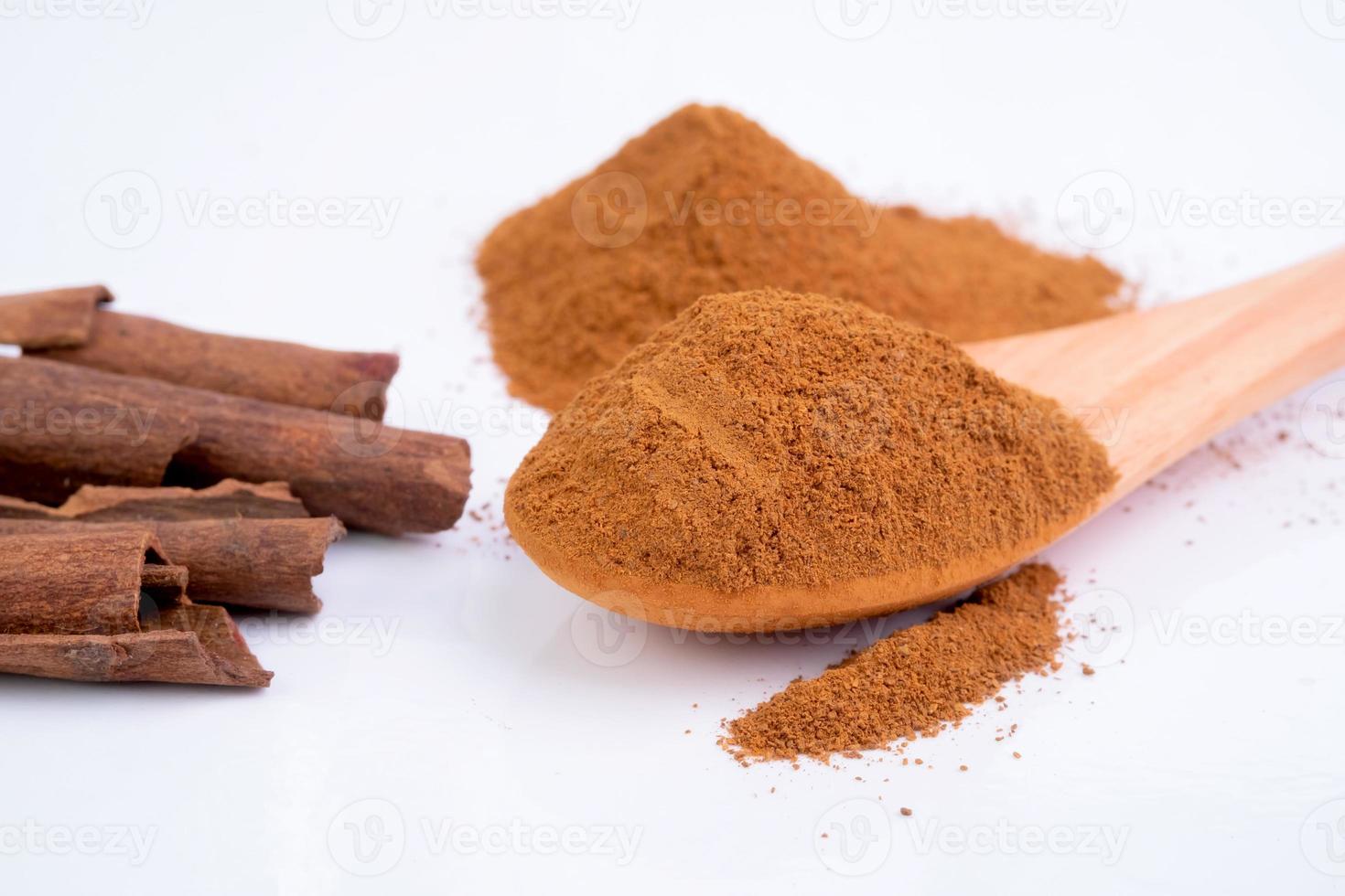 Cinnamon powder with wooden spoon isolated on white background. photo