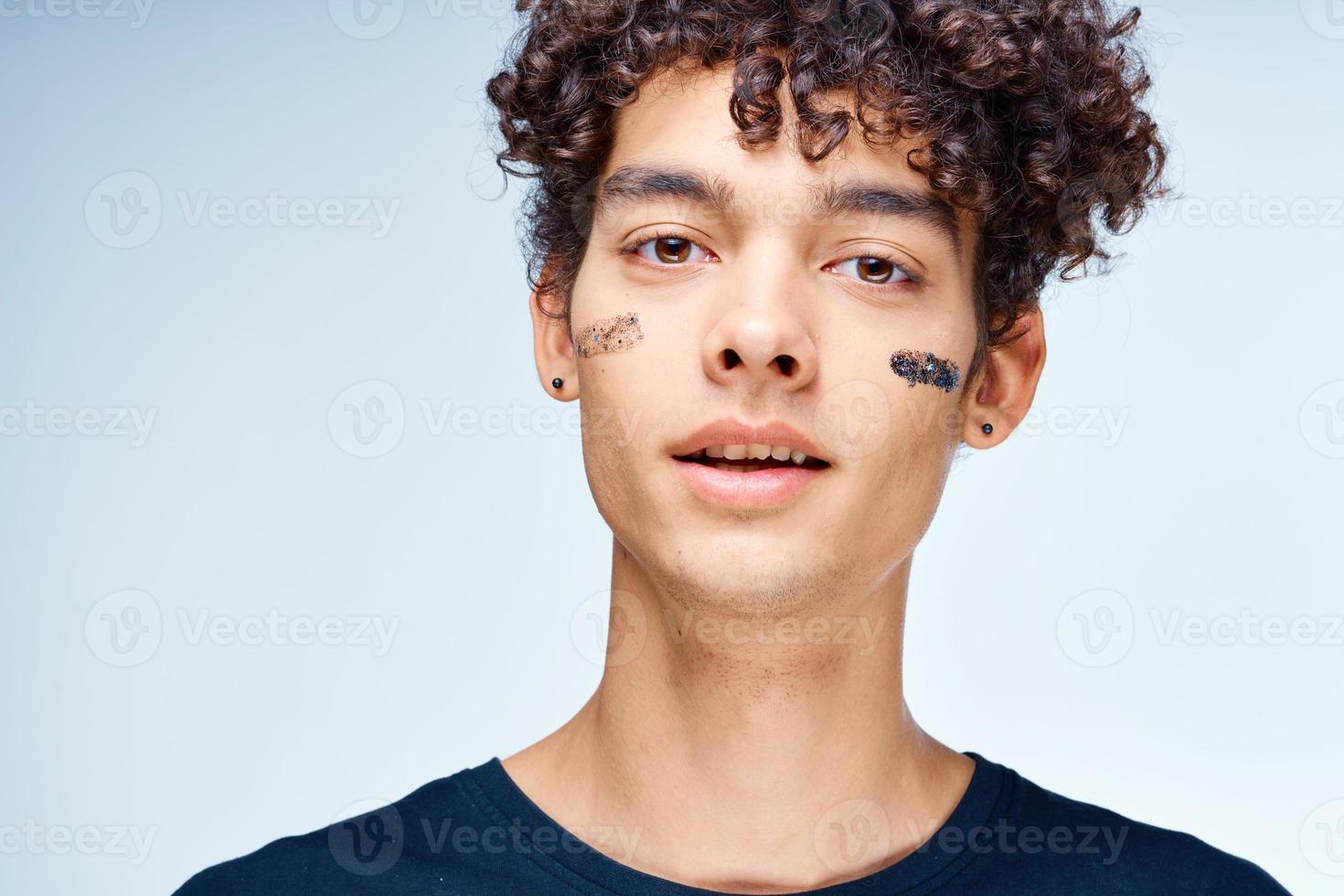 alegre hombre con Rizado pelo productos cosméticos en cara limpiar piel foto