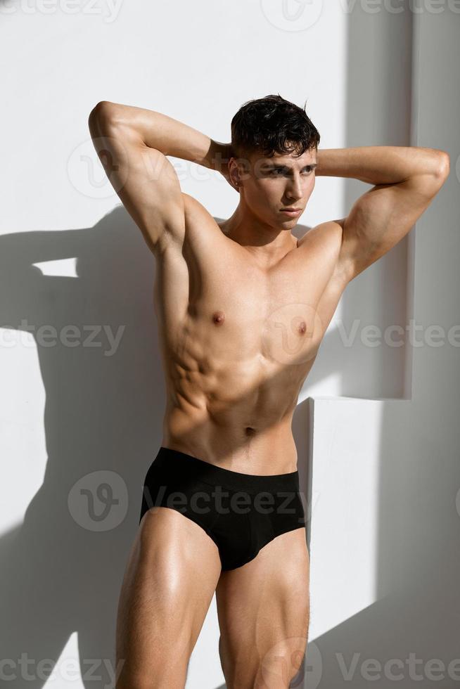 handsome man with pumped up muscular body black underpants basing light background photo