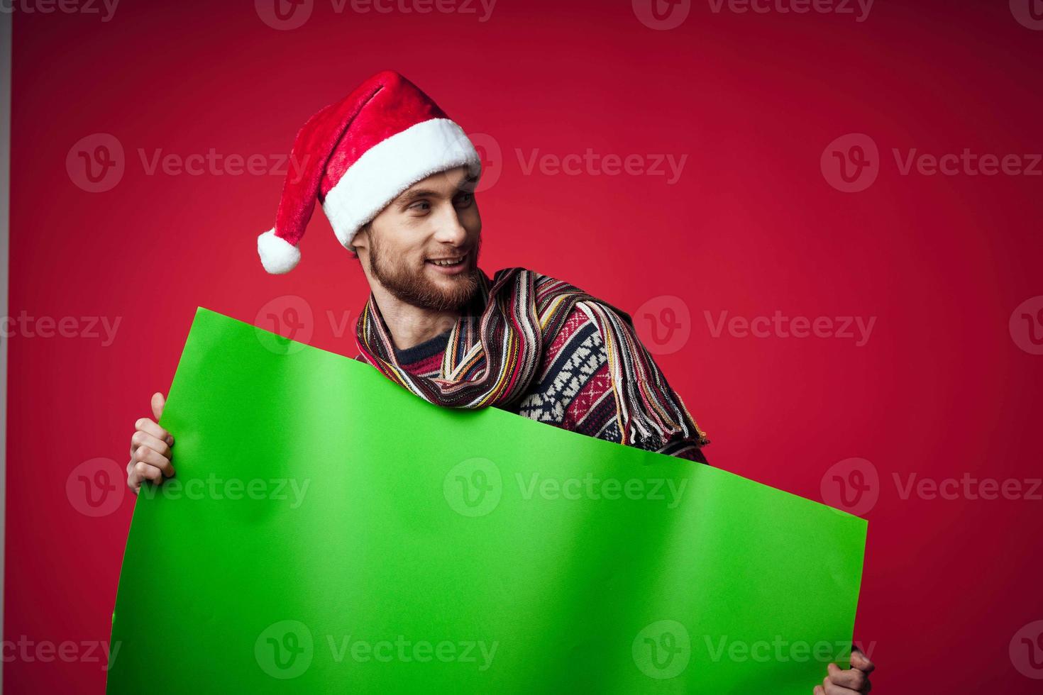 handsome man in a christmas hat with green mockup red background photo