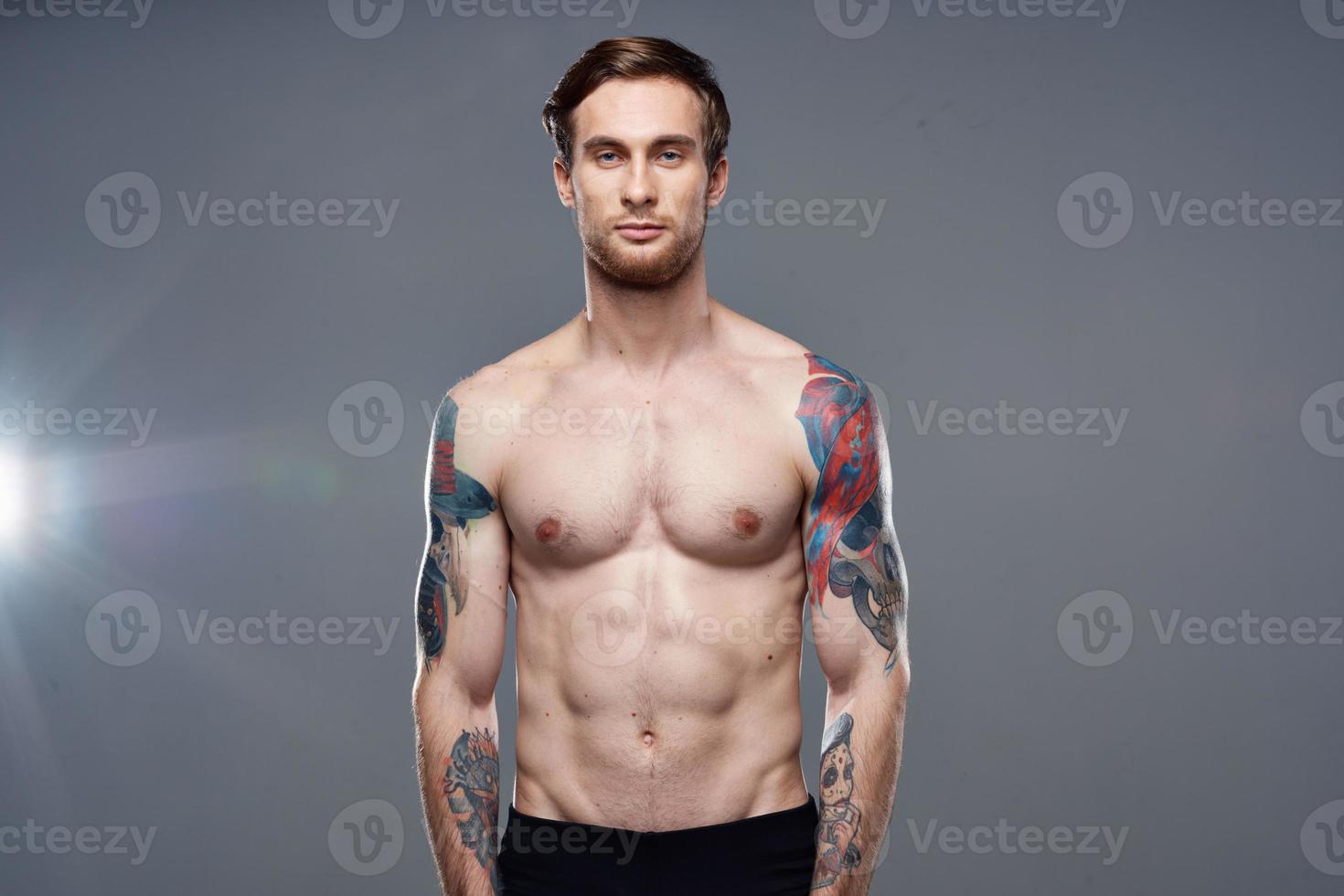 sporty man pumped up press acting out on his arms cropped view gray background photo
