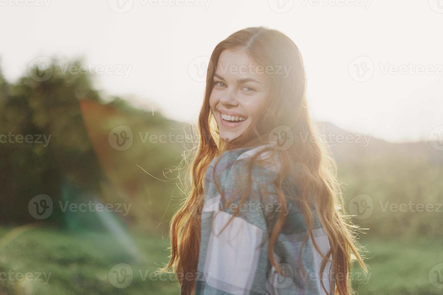 A woman gardener in an apron stands in a field of green grass outdoors, smiling on a summer afternoon into a sunny sunset after a day's work photo