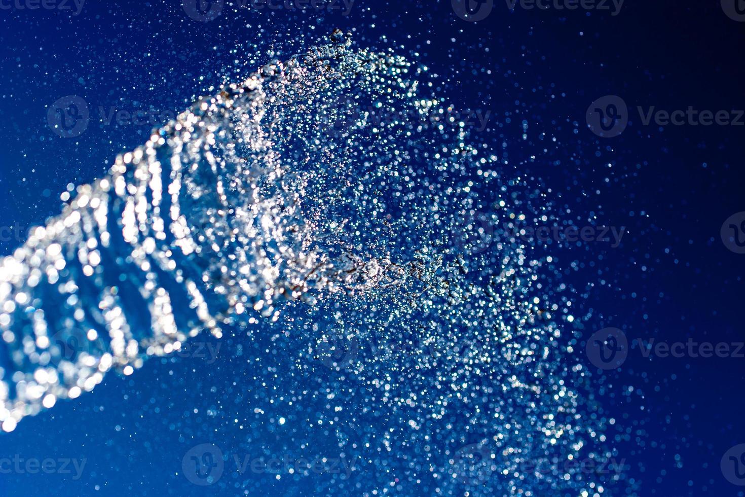 Abstract background. A stream of water with splashes sparkles on a blue background. photo