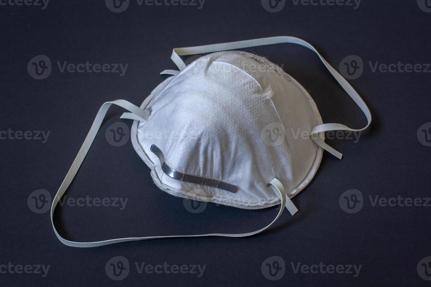 Construction mask on the face to protect the respiratory tract from dust. Protective respirator. Dark background. Horizontal. photo