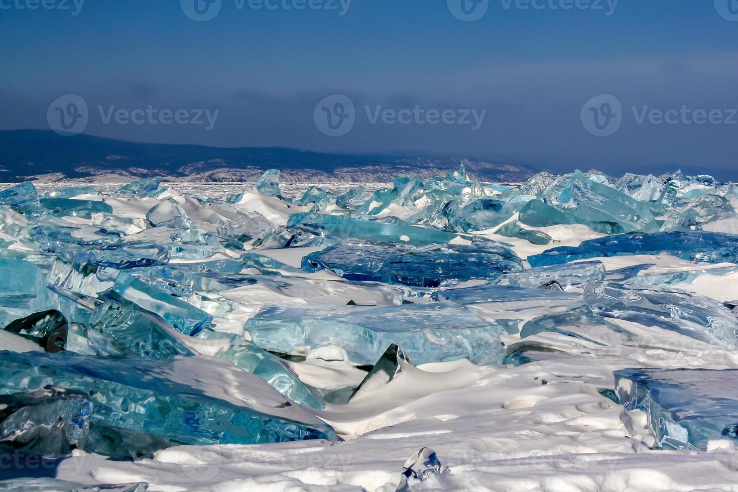 grande hielo montículos de transparente hielo en lago Baikal. el hielo es verde y azul. montañas en el horizonte. oscuro azul cielo. foto