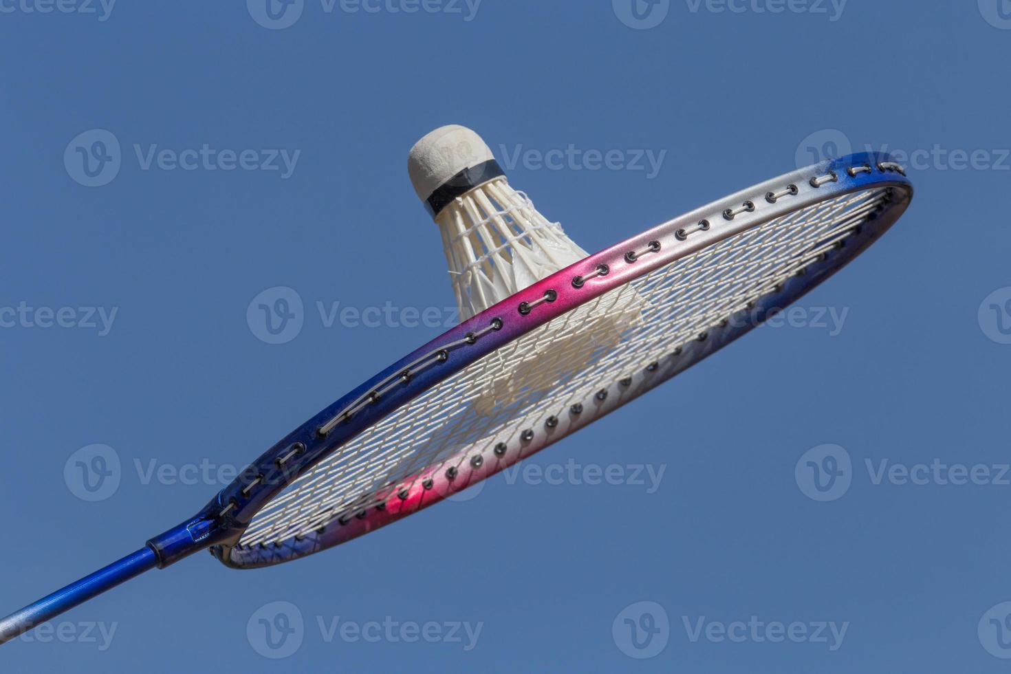 close up of badminton racquet with shuttlecock against blue sky photo