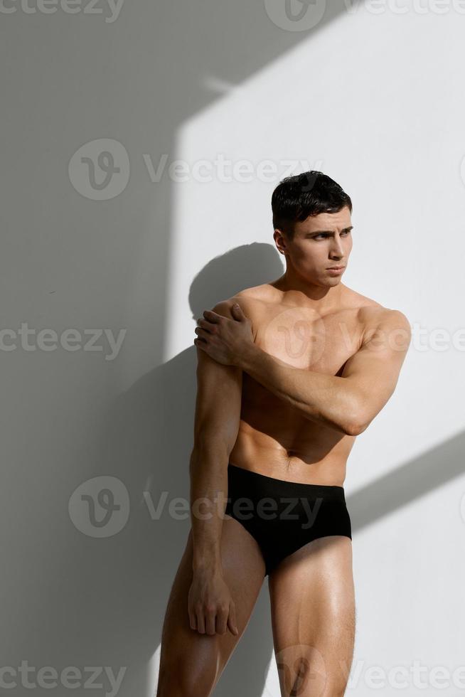 a man with a pumped-up muscular body holds a hand on his head in black panties photo