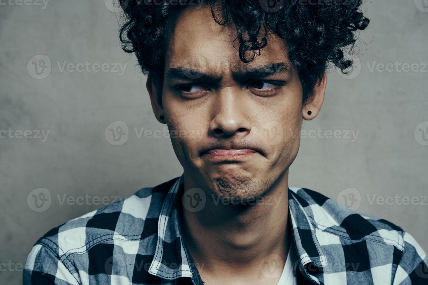 emocional chico en un tartán camisa en un gris antecedentes riendo Confusión tristeza incertidumbre foto