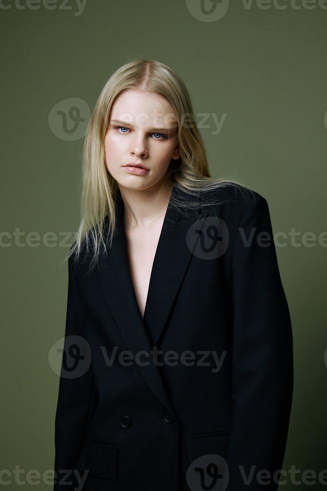 Portrait of a girl in a black jacket posing on a green background in the studio. A concept for marketplaces and clothing brands. photo