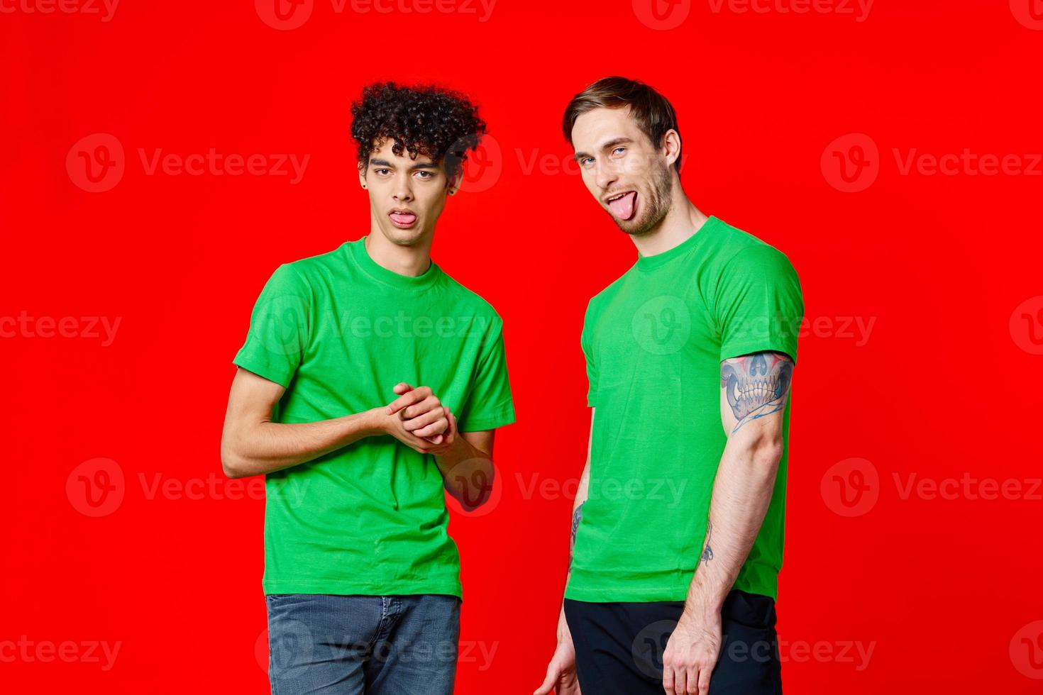 two friends in green t-shirts are standing next to tin with their hands emotions photo