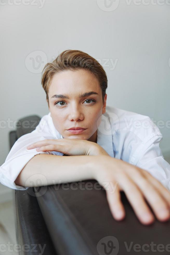 Women lying at home on the couch portrait with a short haircut in a white shirt, smile, depression in teenagers, home holiday photo