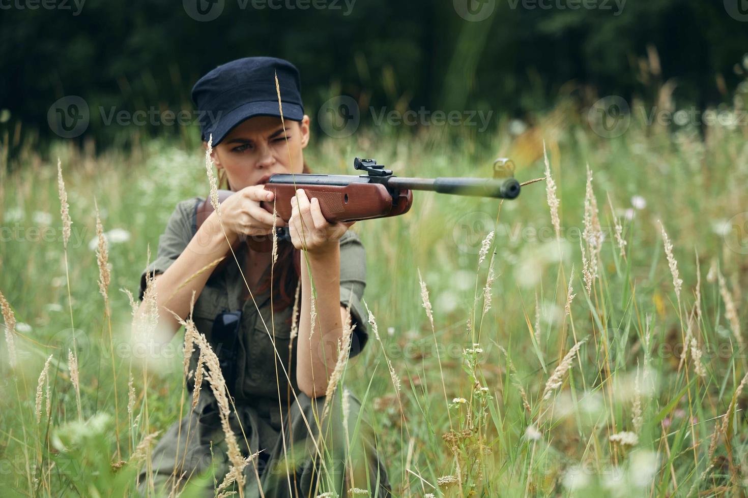 mujer con armas en mano, abrigo puntería verde hojas verde foto