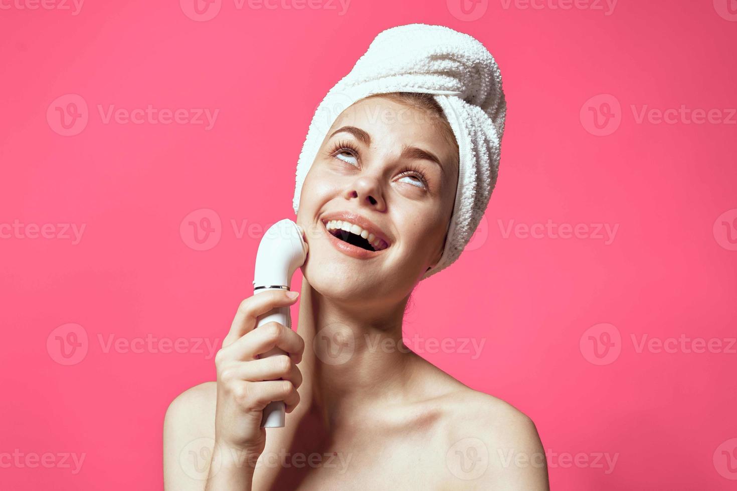 woman with towel on head cleaning skin naked shoulders pink background photo