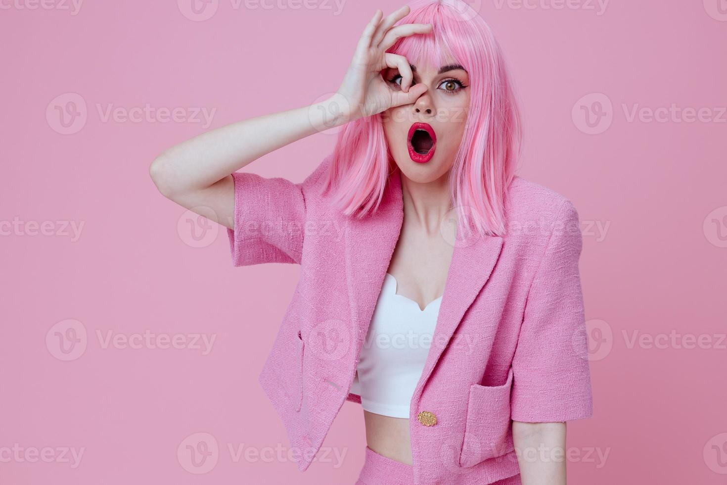 Pretty young female gestures with his hands with a pink jacket pink background unaltered photo