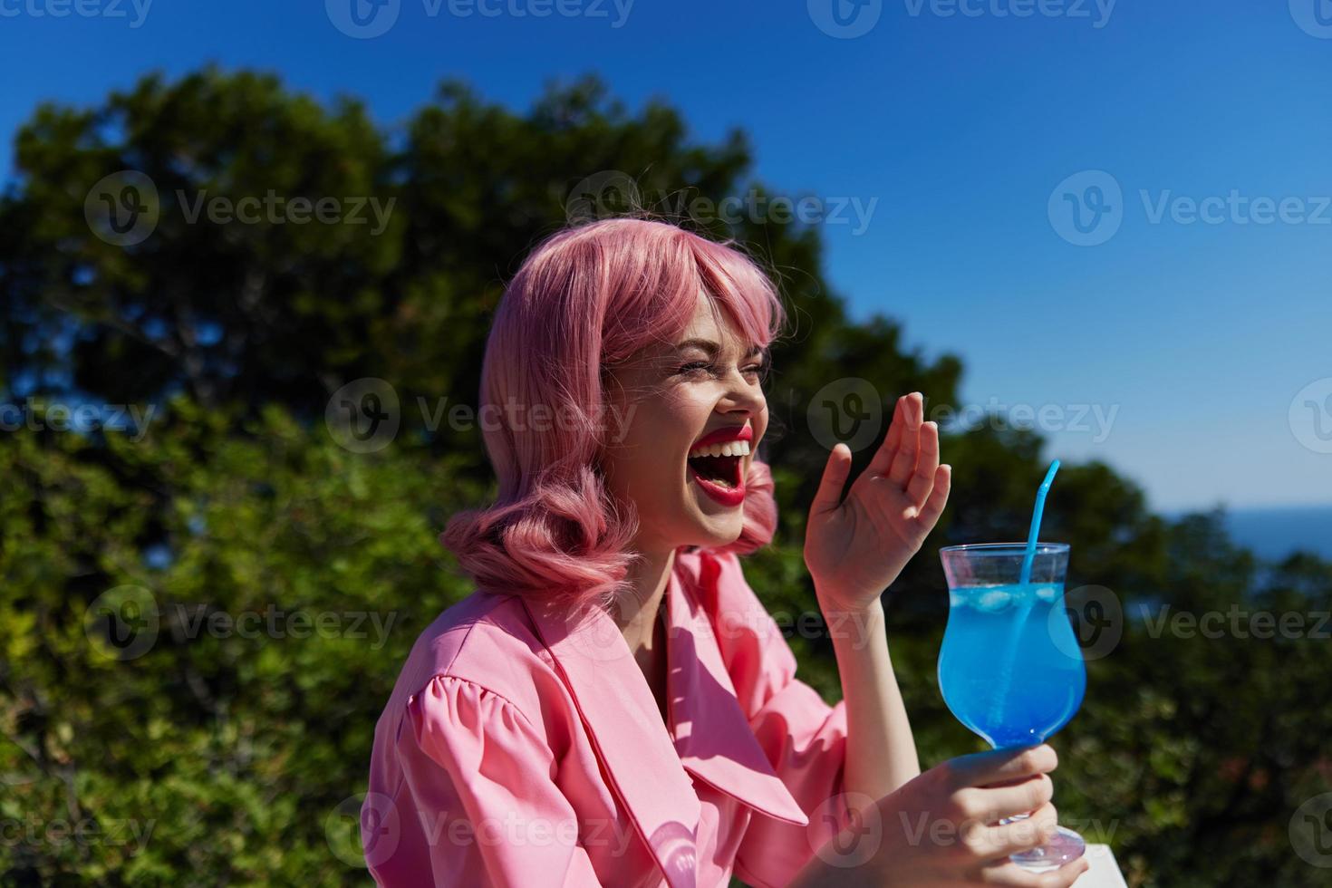 alegre mujer Bebiendo un cóctel en el terraza Bebiendo alcohol foto