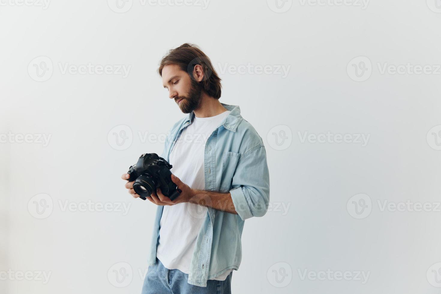 Man hipster photographer in a studio on a white background looking at the camera screen and setting it up for a photo shoot