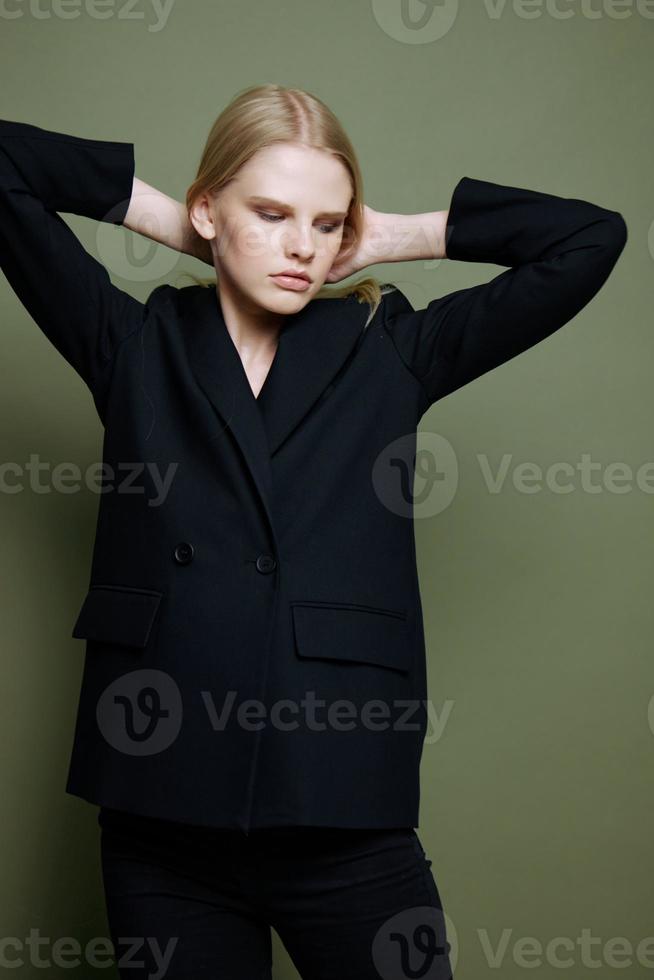 An incredible professional model ties her hair and looks at the camera. Concept photo for clothing brands. Cool offer for fashionable suits