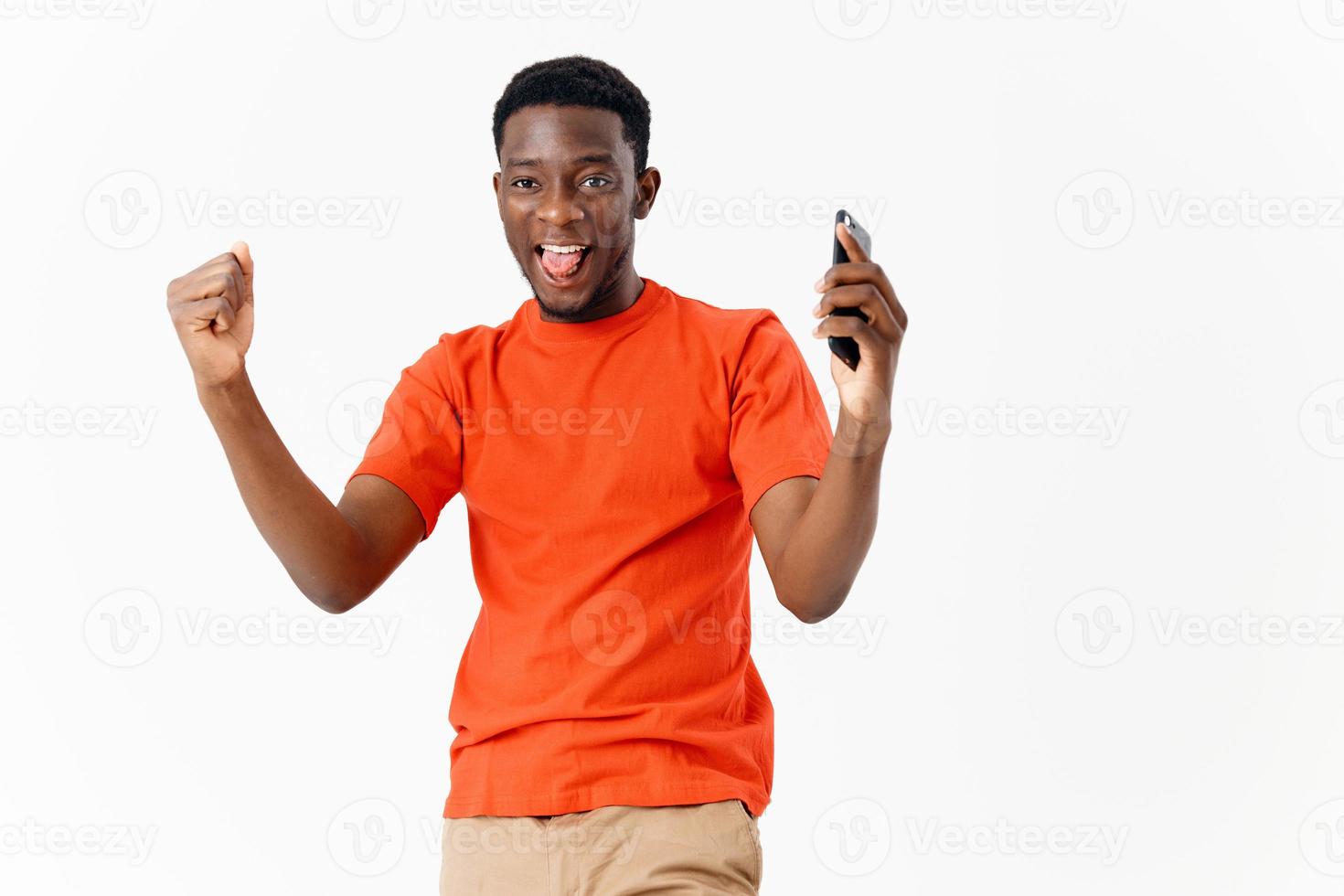 Cheerful African American in an orange t-shirt with a phone in his hands technology emotion photo