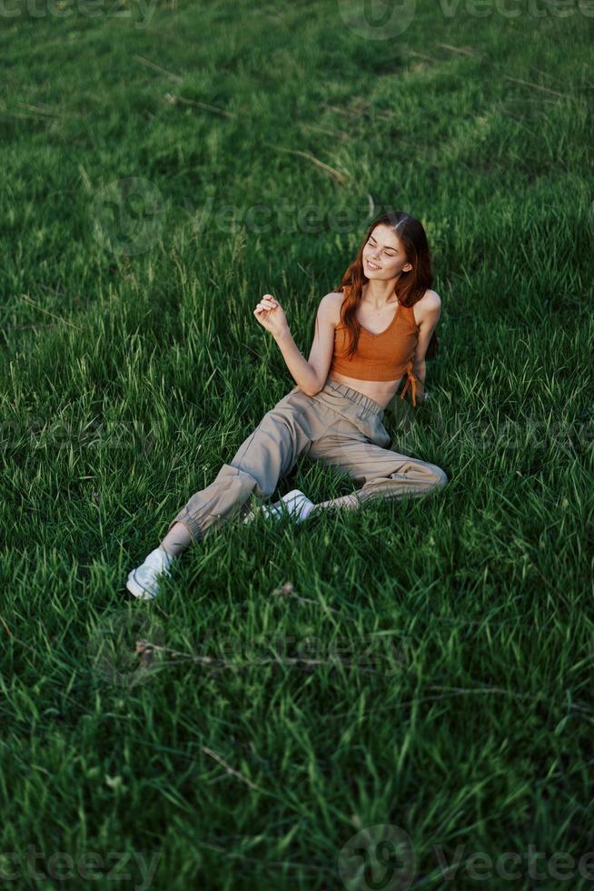 A woman lies on fresh spring green grass in a park without mosquitoes or ticks and enjoys relaxing while watching the sunset. The concept of safe outdoor recreation photo