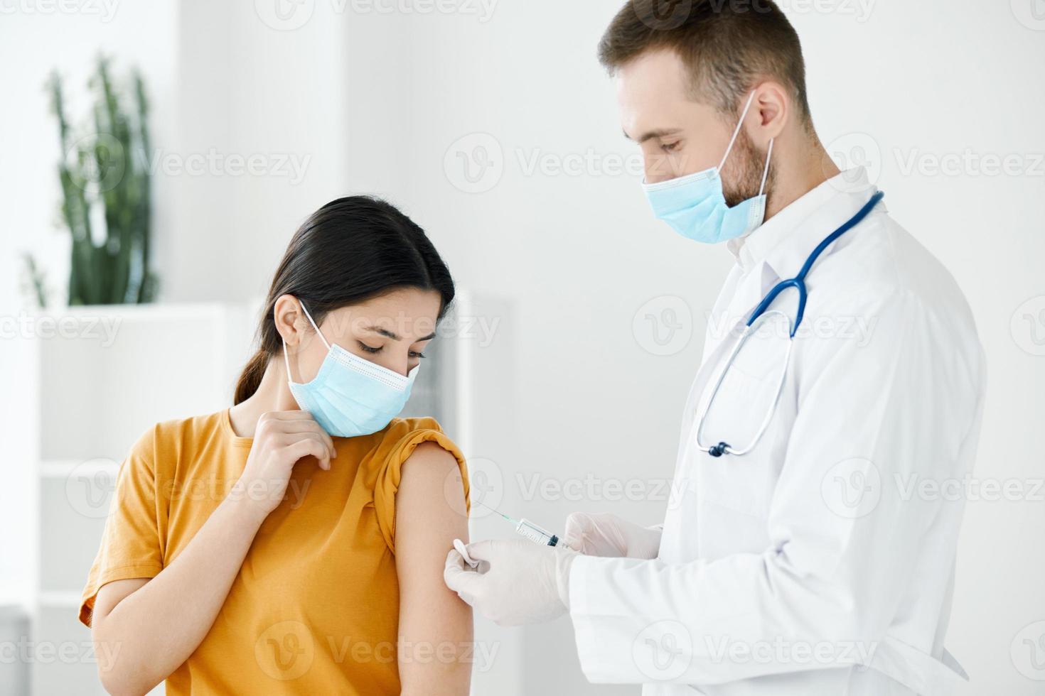 doctor giving a shot to the woman's shoulder medical mask covid-19 vaccine photo