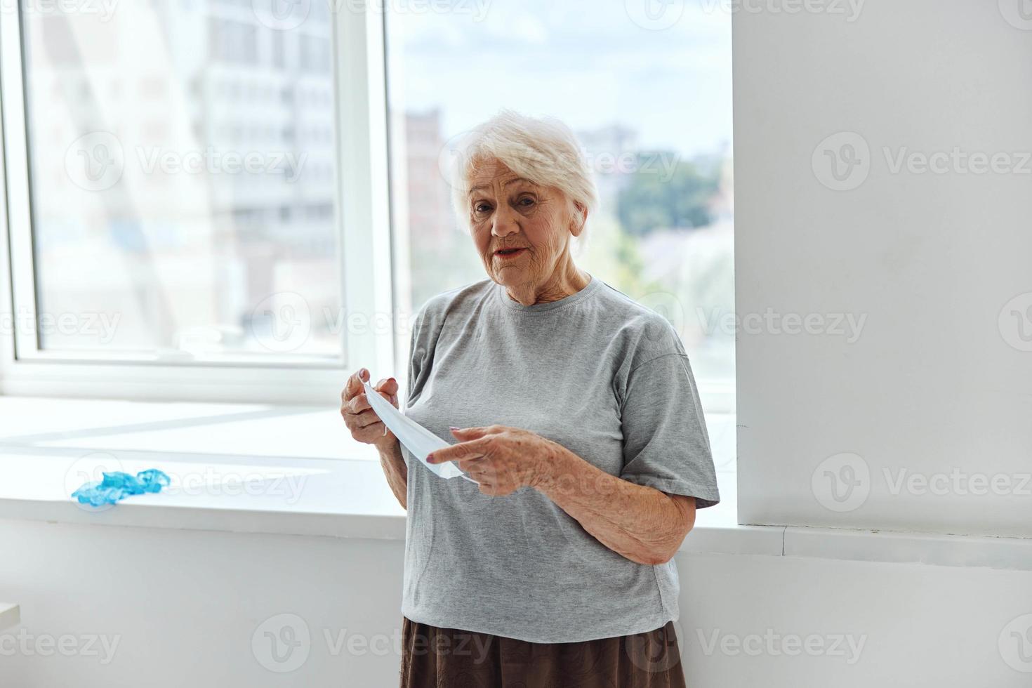 elderly woman near window hospital protection medical mask photo