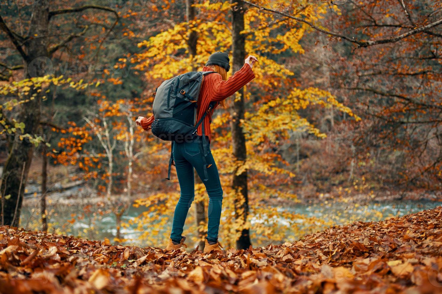 mujer en un suéter y pantalones y botas en otoño en un parque en naturaleza cerca el río foto