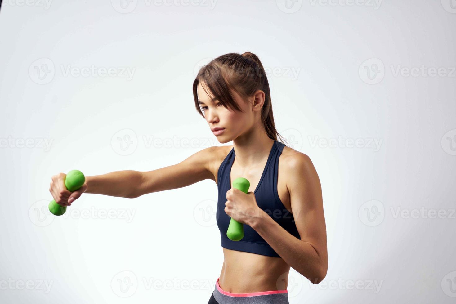 athletic slim woman workout with dumbbells fitness light background photo