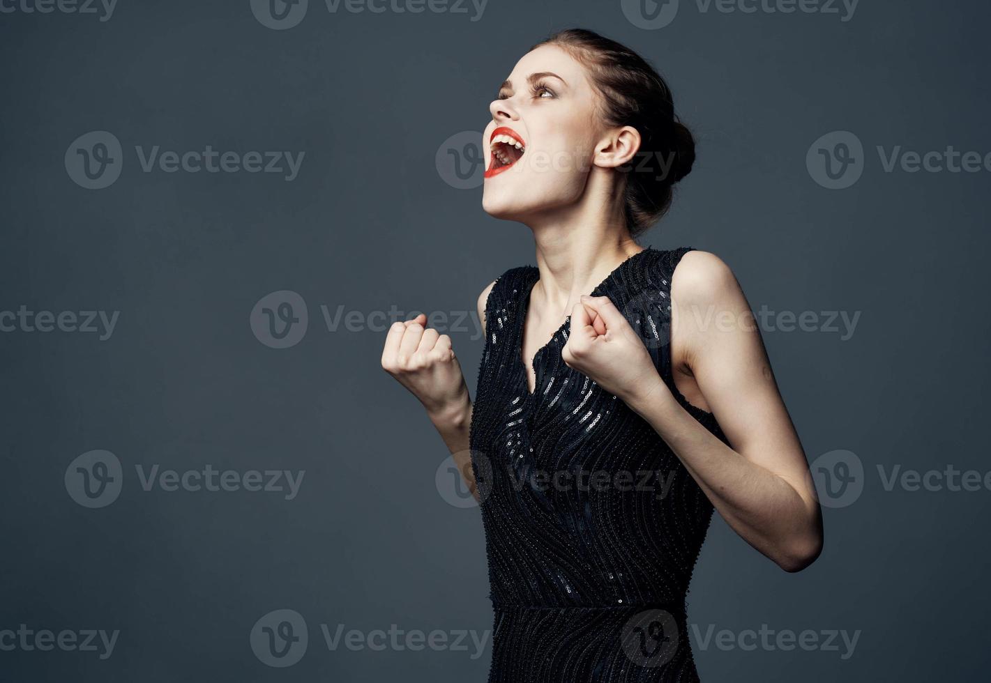 un mujer en un negro vestir gestos con su manos sorpresa deleite emociones foto