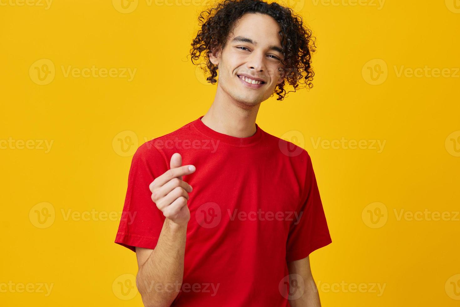 encantador gracioso caucásico joven hombre en rojo camiseta espectáculo corazón forma gesto posando aislado en terminado amarillo estudio antecedentes. el mejor oferta con gratis sitio para publicidad. emociones para todos los días concepto foto