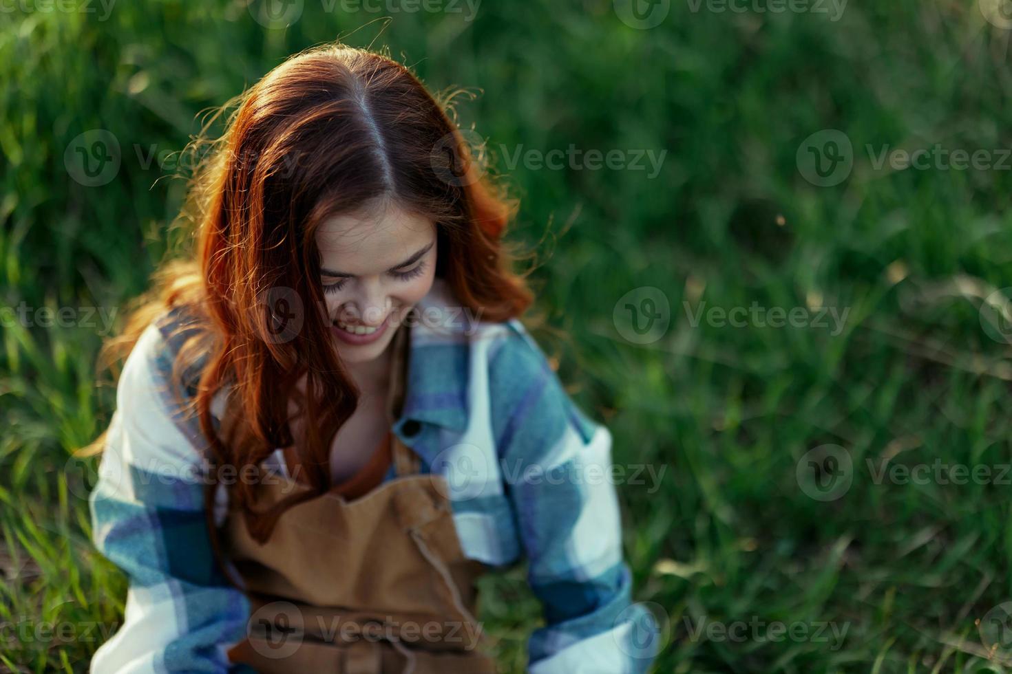 Woman lying on the grass smiling playing and cuddling her dog in nature in the park in the summer sunset. The concept of health and love of animals, treatment of ticks and fleas grass and animals photo