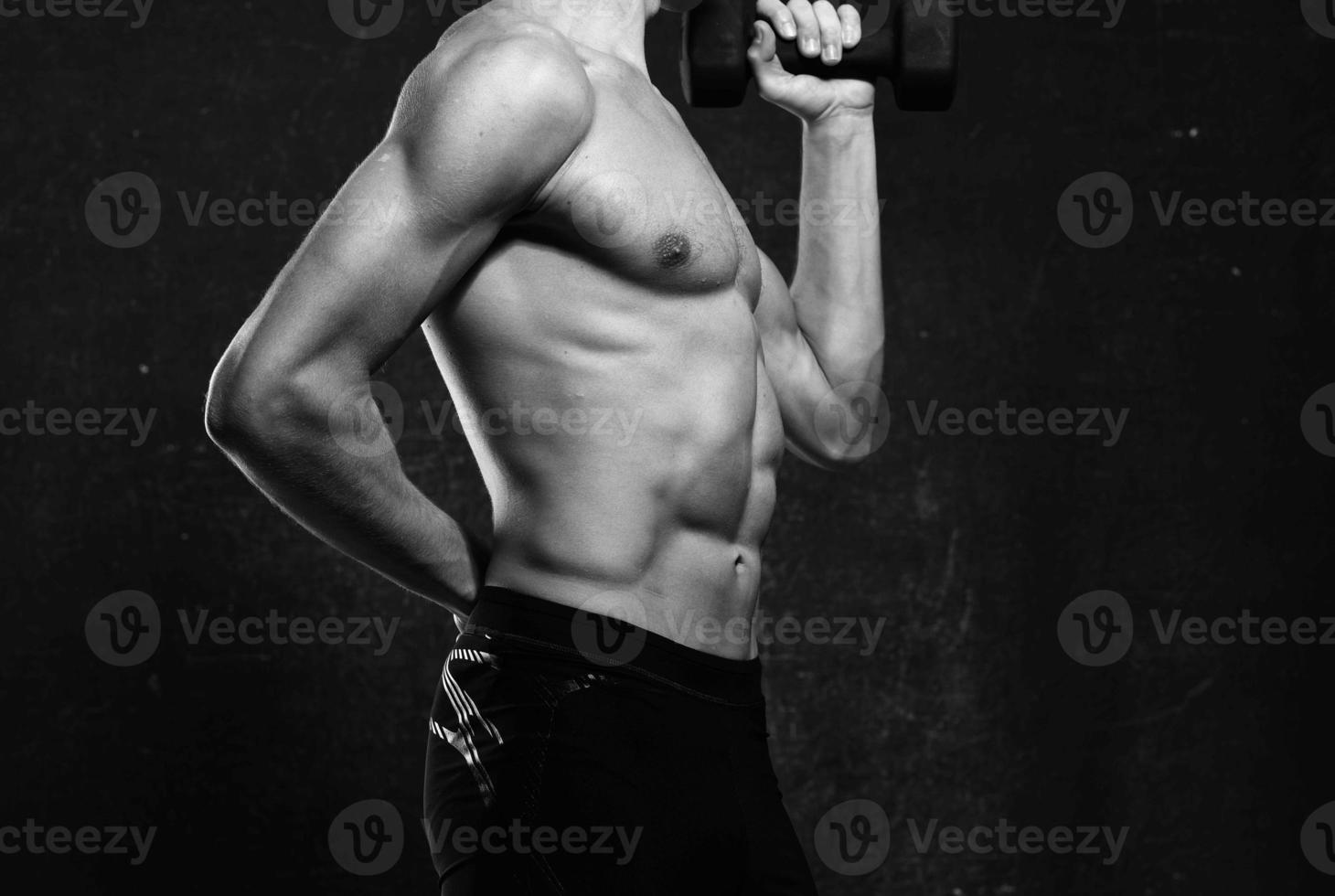 sporty man naked torso inflated body posing dark background photo