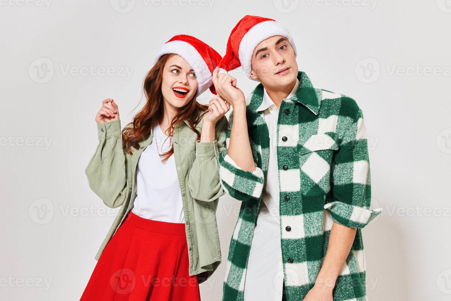 Enamored young people in Christmas hats on a light background gestures with their hands photo