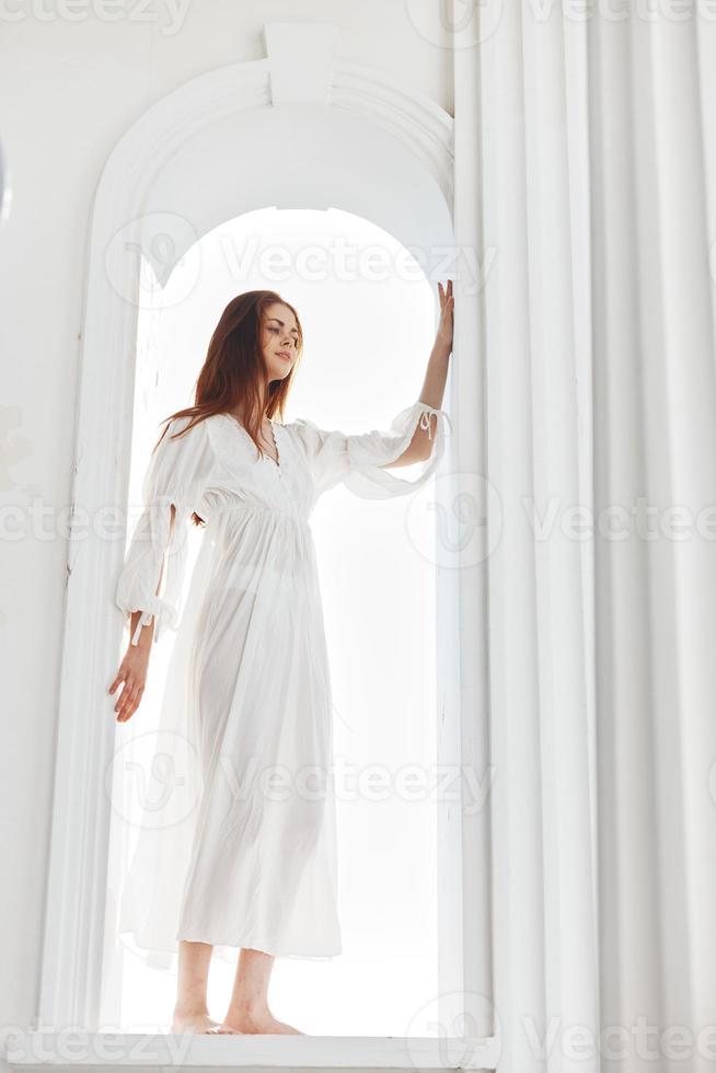 Woman in a white dress in the opening in the form of an arch posing photo