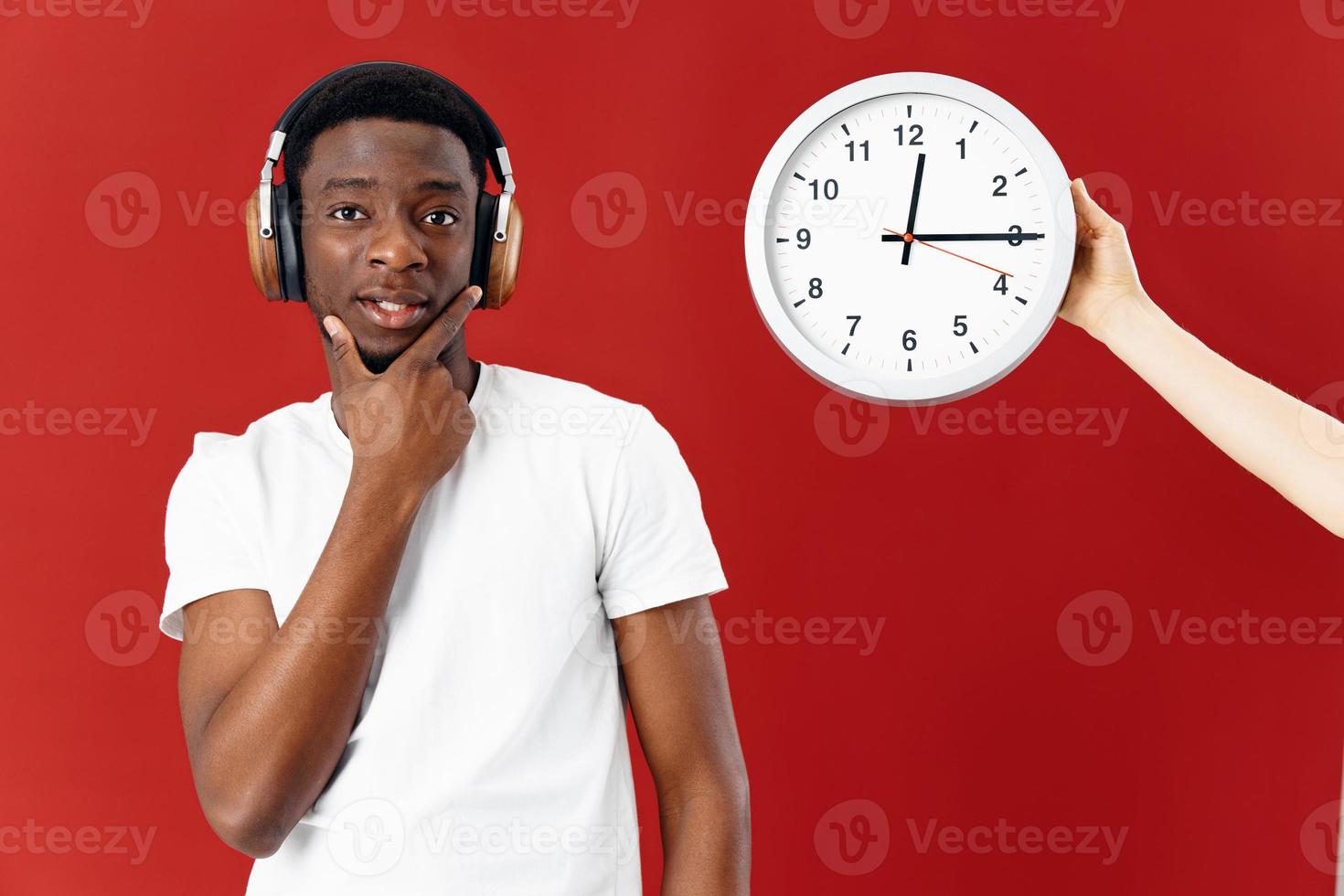 man of african appearance in headphones next to clock in white t-shirt cropped view photo