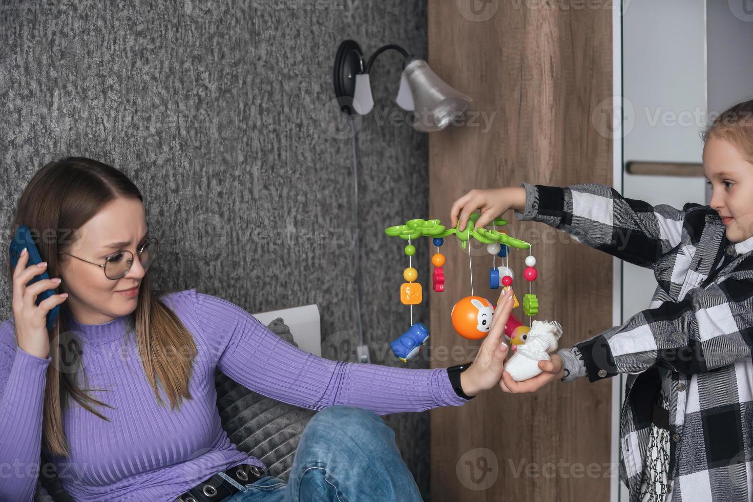 The girl asks her mother to give birth to her little brother or sister, the mother is talking on the phone and refuses her daughter. Women's unwillingness to have children, one child in the family photo