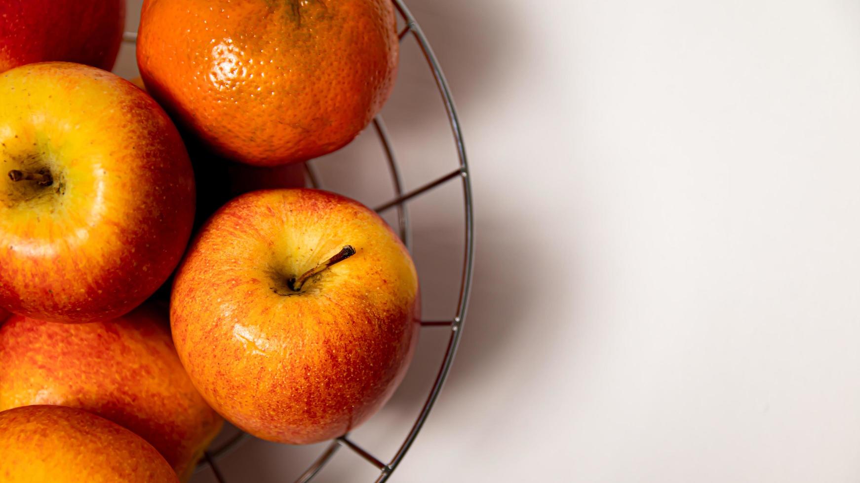 Ripe apples and tangerines in a metal basket on a white background photo