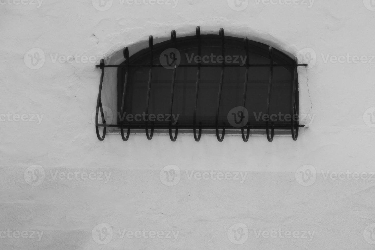 dark window with a grille on a white wall photo